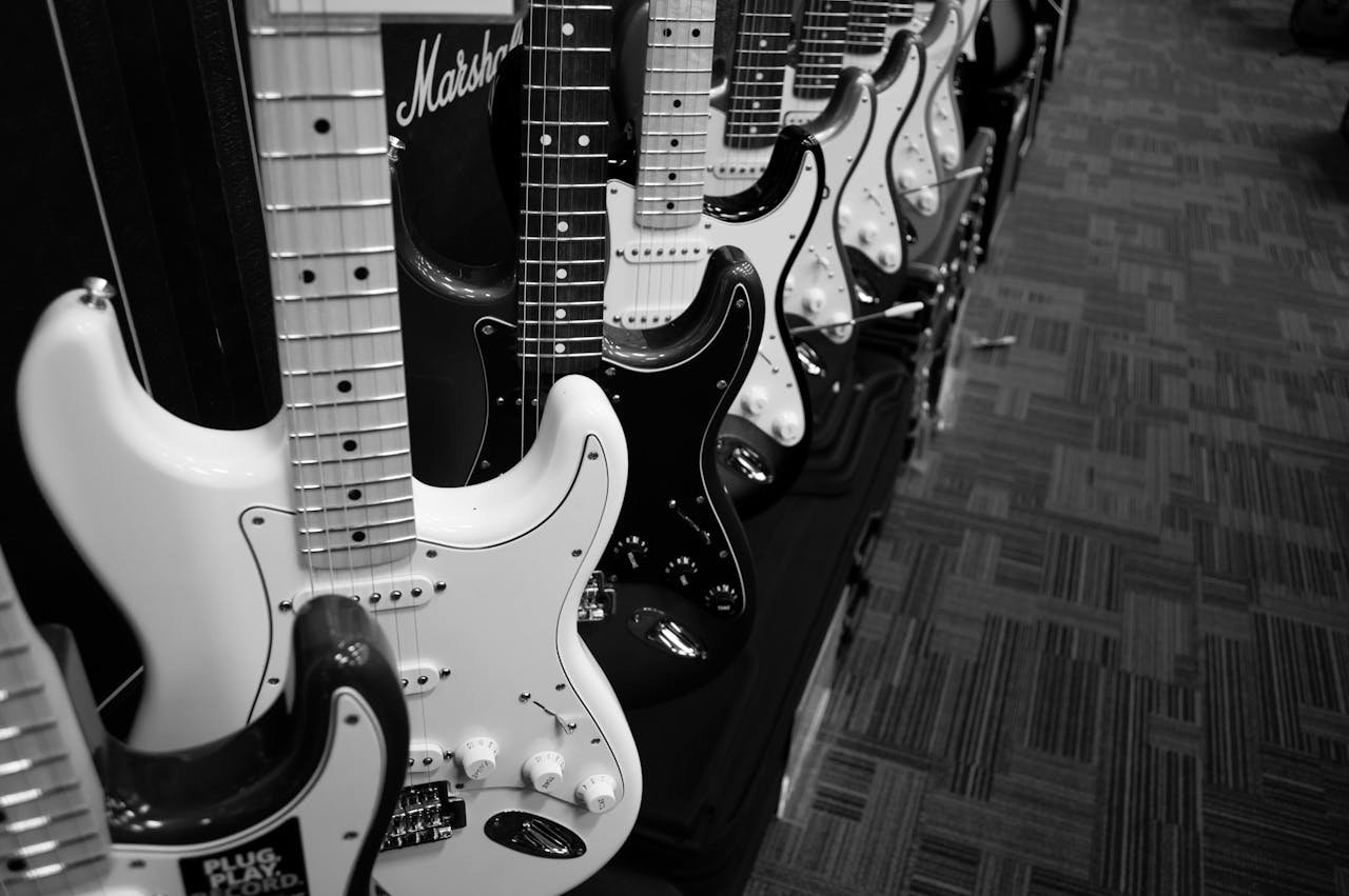 Black and white photo featuring a row of electric guitars in a music shop.